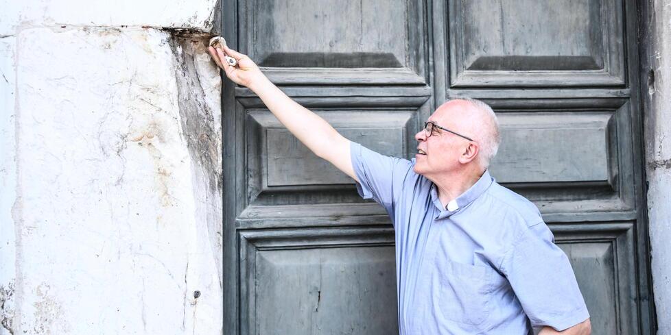 Don Malanca tiene in mano alcuni frammenti e indica il punto da cui è stato spezzato il blocco di marmo