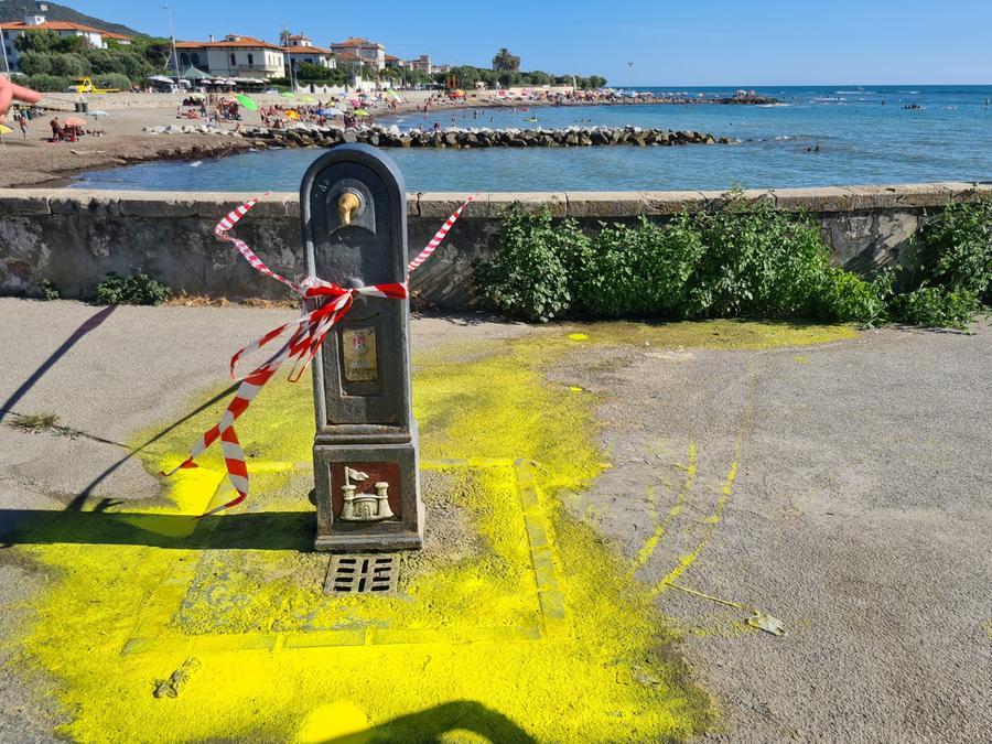 Operaio lava un barattolo di vernice alla fontanella pubblica