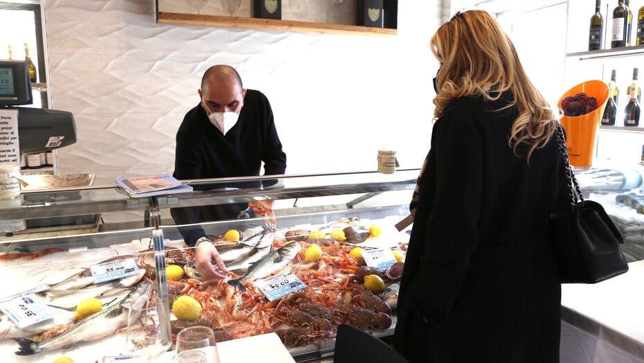 Maurizio Frati all'interno della risto-pescheria "Il Porto" di via San Giovanni mentre serva un cliente (foto Pentafoto/Archivio Tirreno)