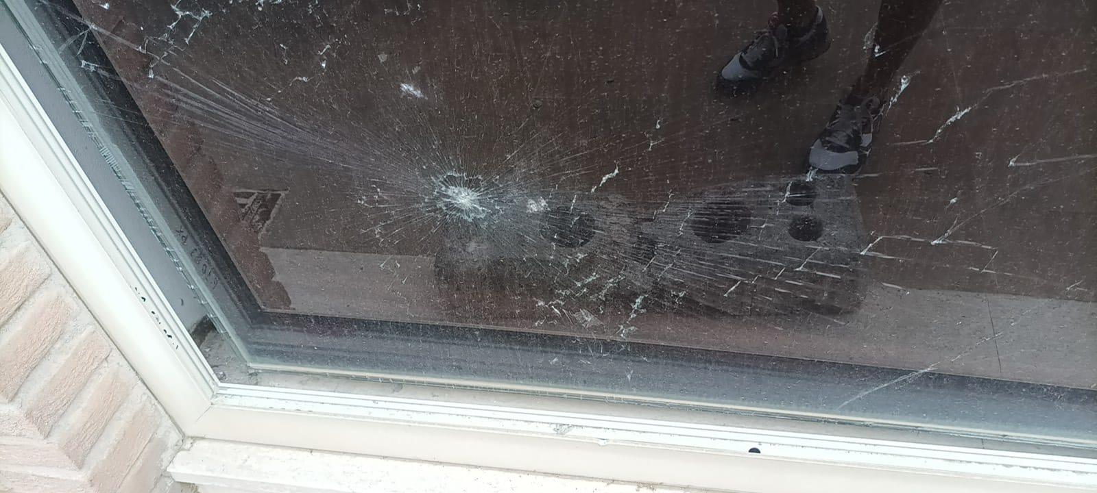 I danni alla vetrata e nel riflesso il mattone utilizzato come ariete