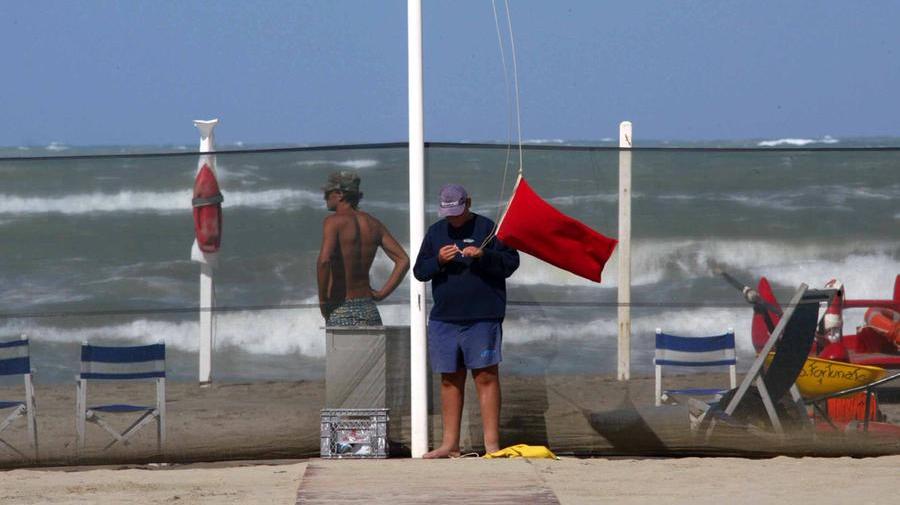 SPIAGGIA LIBERA
un bagnino alza la bandiera rossa che segnala di non fare il bagno in mare per il forte vento
