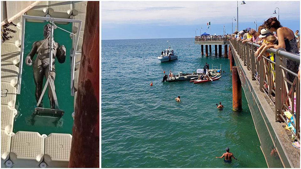 La folla che segue le operazioni dal pontile e uno dei due bronzi che viene inabissato