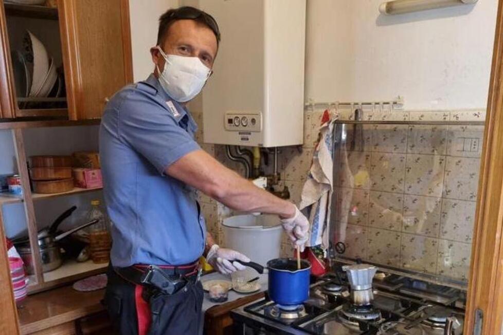 Un carabiniere mentre cucina un piatto di pasta per l’anziano