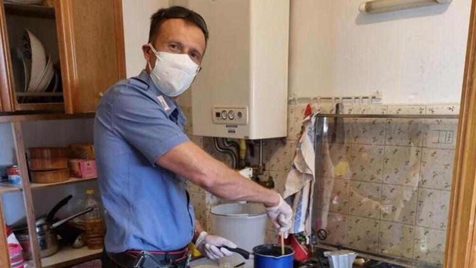 Un carabiniere mentre cucina un piatto di pasta per l’anziano