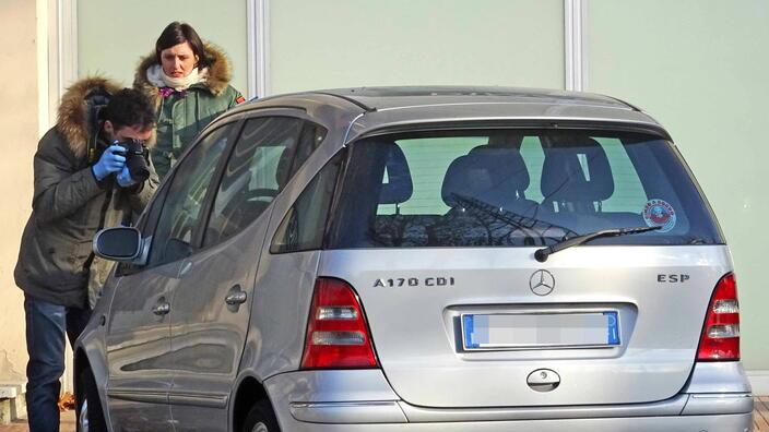 Due agenti della polizia scientifica al lavoro su una bottiglia di gasolio lasciata su un’auto in sosta in un posteggio (immagine d’archivio)
