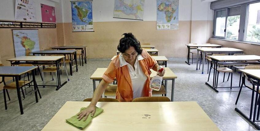 Una bidella sanifica un’aula (foto d’archivio)