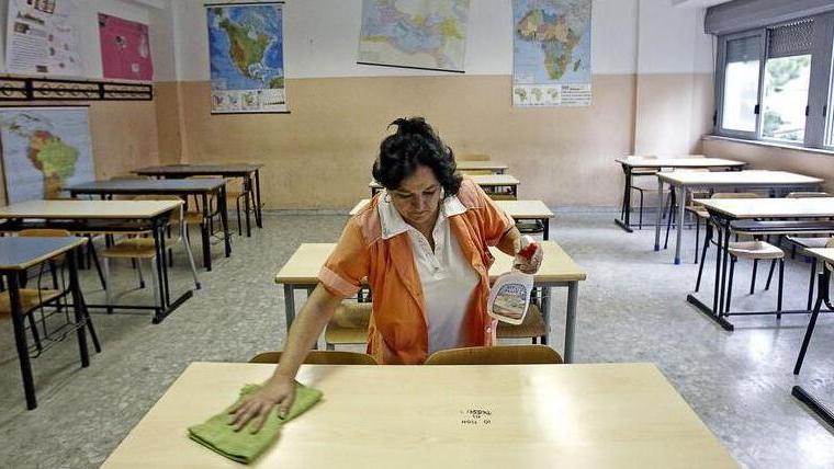 Una bidella sanifica un’aula (foto d’archivio)