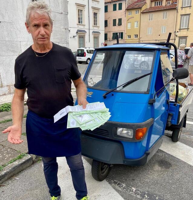 Roi Pantaleoni con in mano le multe e dietro l’Ape Piaggio che usa per entrare in centro