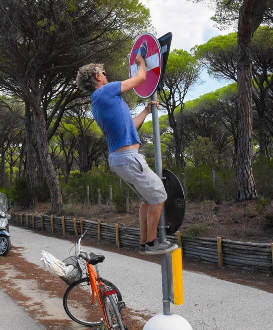 L’artista mentre applica uno sticker a un cartello