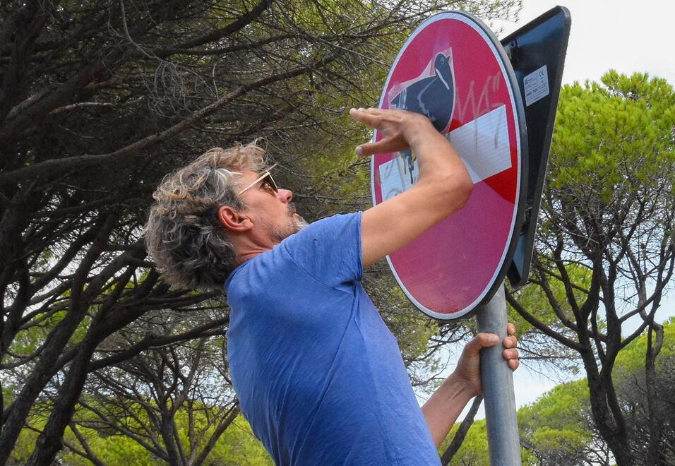 Clet Abraham mentre dipinge uno dei cartelli stradali all’interno del Parco della Maremma