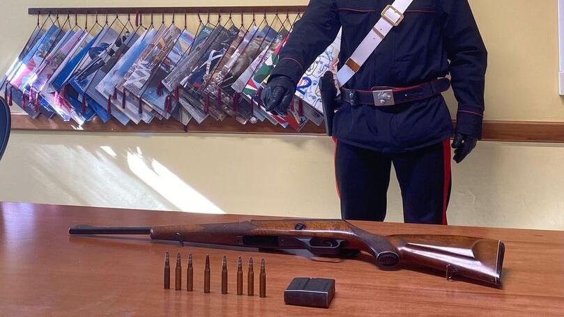 Un carabiniere indica arma e munizioni sequestrate al cacciatore di frodo