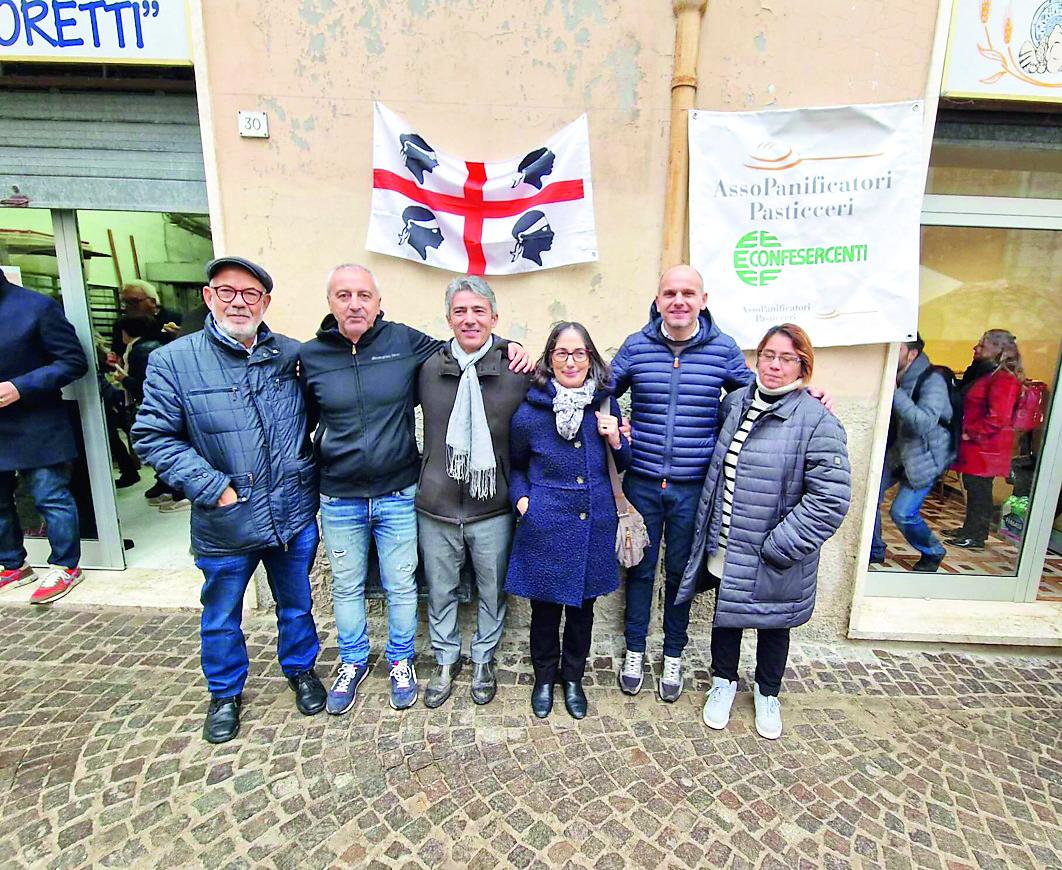 Foto di gruppo davanti allo storico panificio “I Moretti” di Cantiano rinato dopo l’alluvione di settembre scorso. Al centro, con la sciarpa, il presidente Fasi Bastianino Mossa e la presidente del circolo di Pesaro Ninna Cabiddu