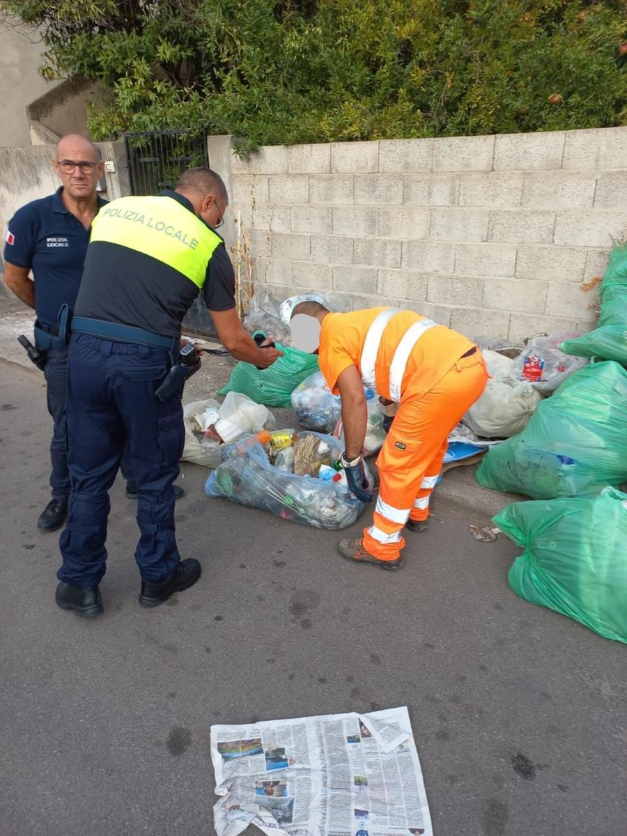
	Polizia locale e addetti al servizio di raccolta dei rifiuti verificano alcuni sacchi

