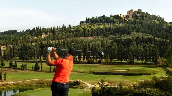 Una immagine del campo da golf della tenuta di Castelfalfi e sullo sfondo il borgo dove si trova il resort