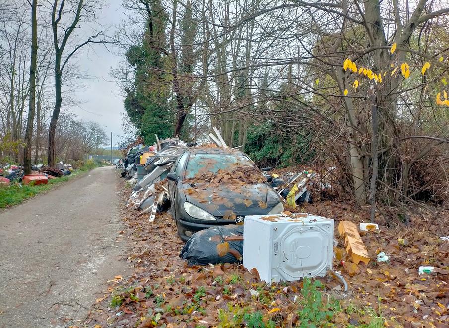 Un’auto spunta dal grande cumulo di rifiuti abbandonati sulla strada che porta al campo nomadi