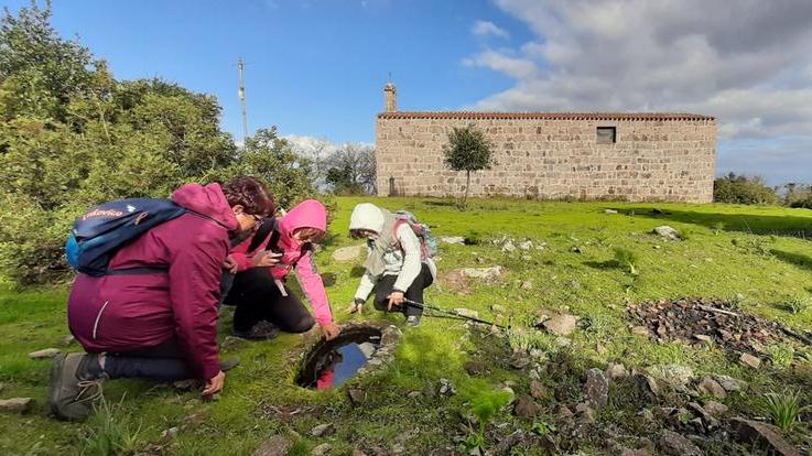 Pellegrini osservano alcune emergenze archeologiche lungo il Cammino del lago Omodeo (foto dal sito www.camminodelagomodeo.it)