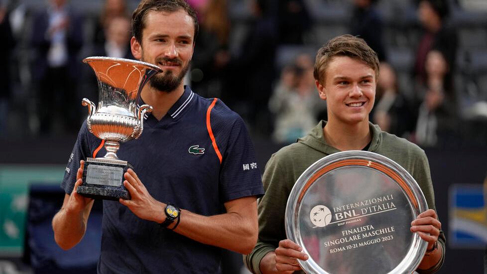Daniil Medvedev con la coppa degli Internazionali d’Italia dopo il successo su Rune (a destra)