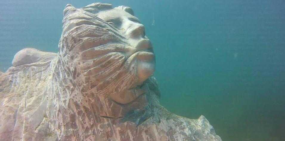 una scultura della Casa dei pesci nel mare di Talamone