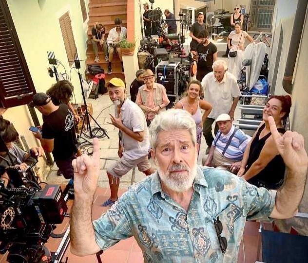 
	Alessandro Benvenuti in un selfie con alle spalle la troupe dei Delitti del BarLume

