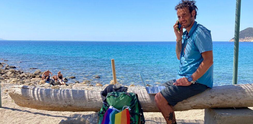 Davide Fiz col suo zaino, il telefono e il computer mentre lavora in smart working durante una delle sue camminate