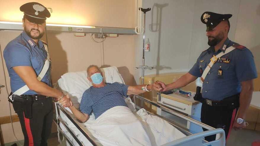 Il 78enne Albo Corallini nel suo letto di ospedale a Villamarina durante l’incontro con i due carabinieri che lo hanno salvato: il vicebrigadiere Pasquale Giordano (a sinistra) e l’appuntato scelto Nicola Rossi
