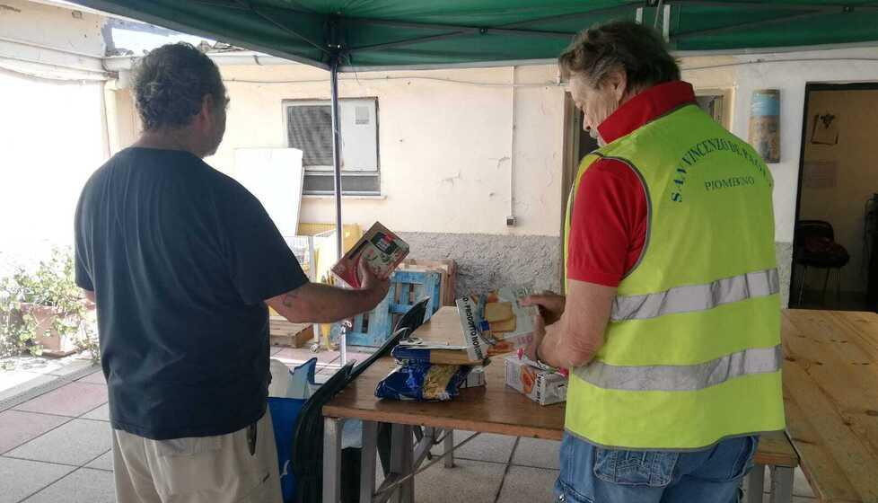 Volontari della San Vincenzo de’ Paoli mentre preparano un pacco alimentare