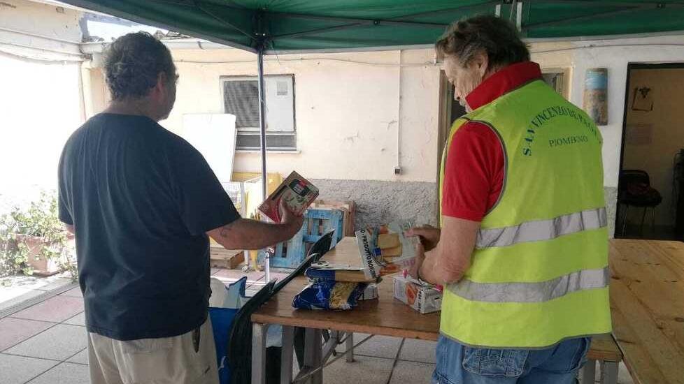 Volontari della San Vincenzo de’ Paoli mentre preparano un pacco alimentare