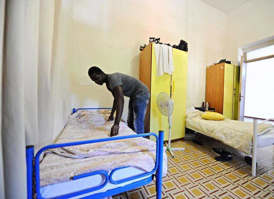 Un richedente asilo mentre rifà il letto nella struttura di accoglienza (foto d’archivio)