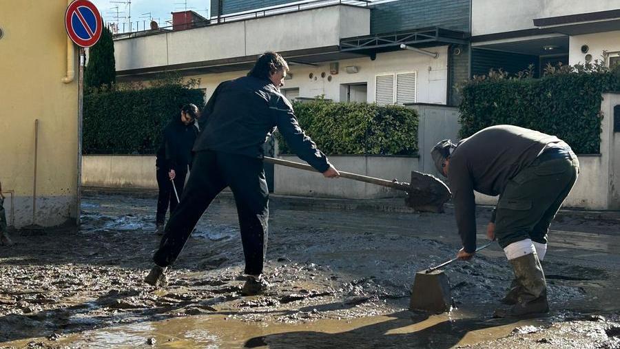 Residenti e volontari impegnati a spalare il fango nelle zone alluvionate