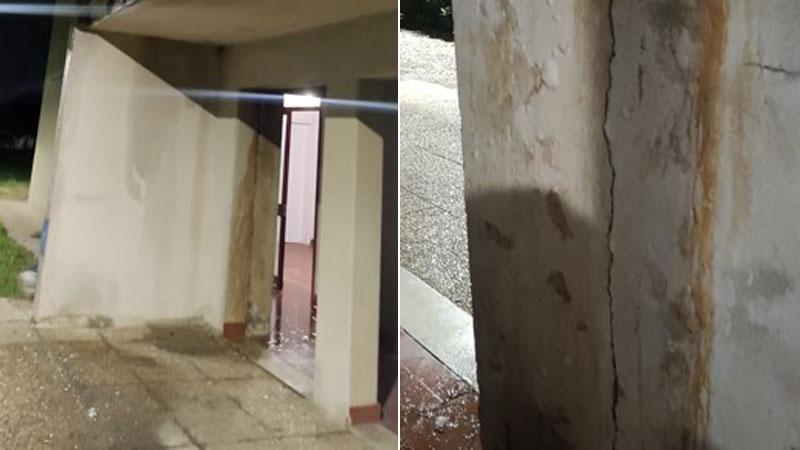L’ingresso del palazzo allagato a causa della perdita d’acqua lungo la parete esterna e, a destra, una delle crepe formatasi lungo la colonna portante della palazzina