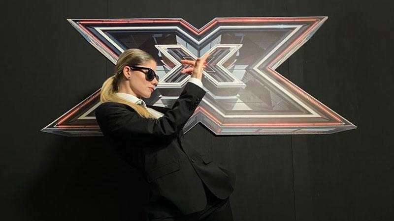 Francesca Lari di fronte allo stemma celebre di X Factor