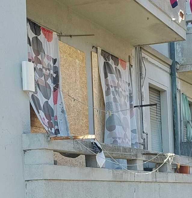 Una finestra chiusa con barriere in legno alla casa popolare occupata in via Pisana