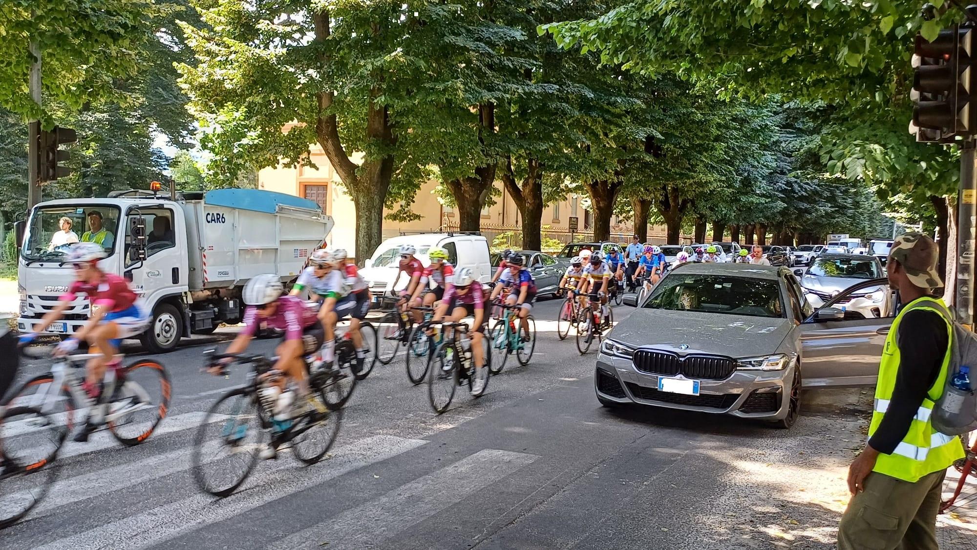 Le atlete che passano in mezzo alle due fila di auto