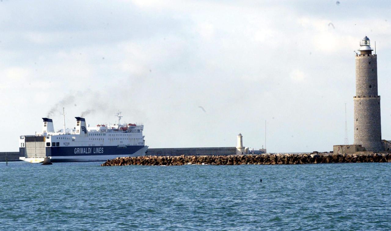 
	Un traghetto supera il faro uscendo dal porto

