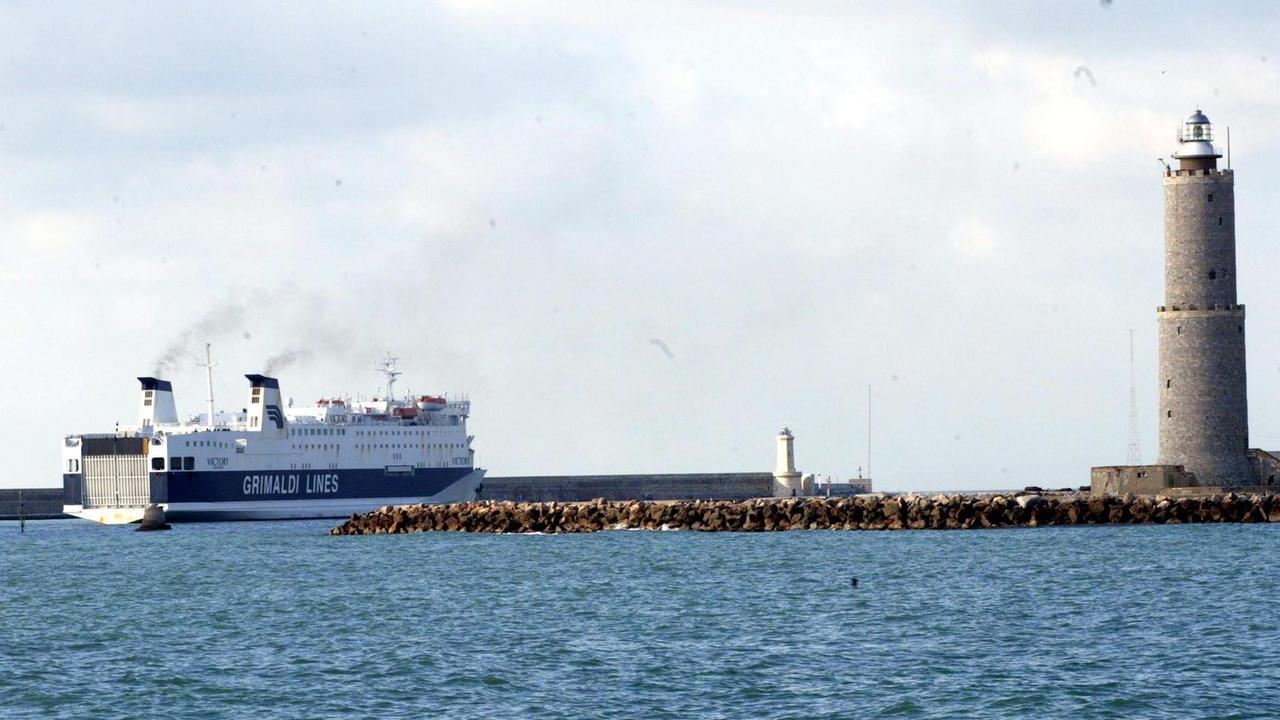Un traghetto supera il faro uscendo dal porto