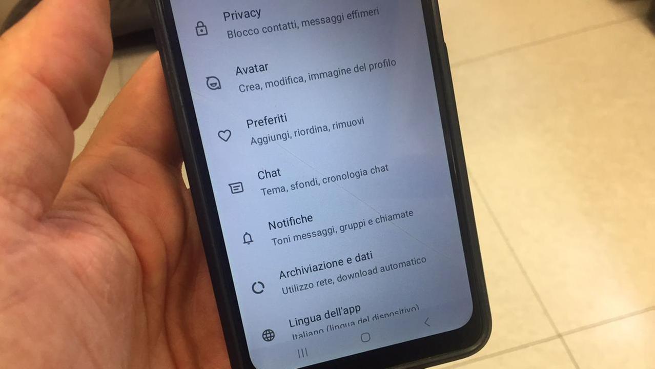 Un uomo mentre tiene in mano un cellulare con aperta l'app di Whatsapp (foto d'archivio)