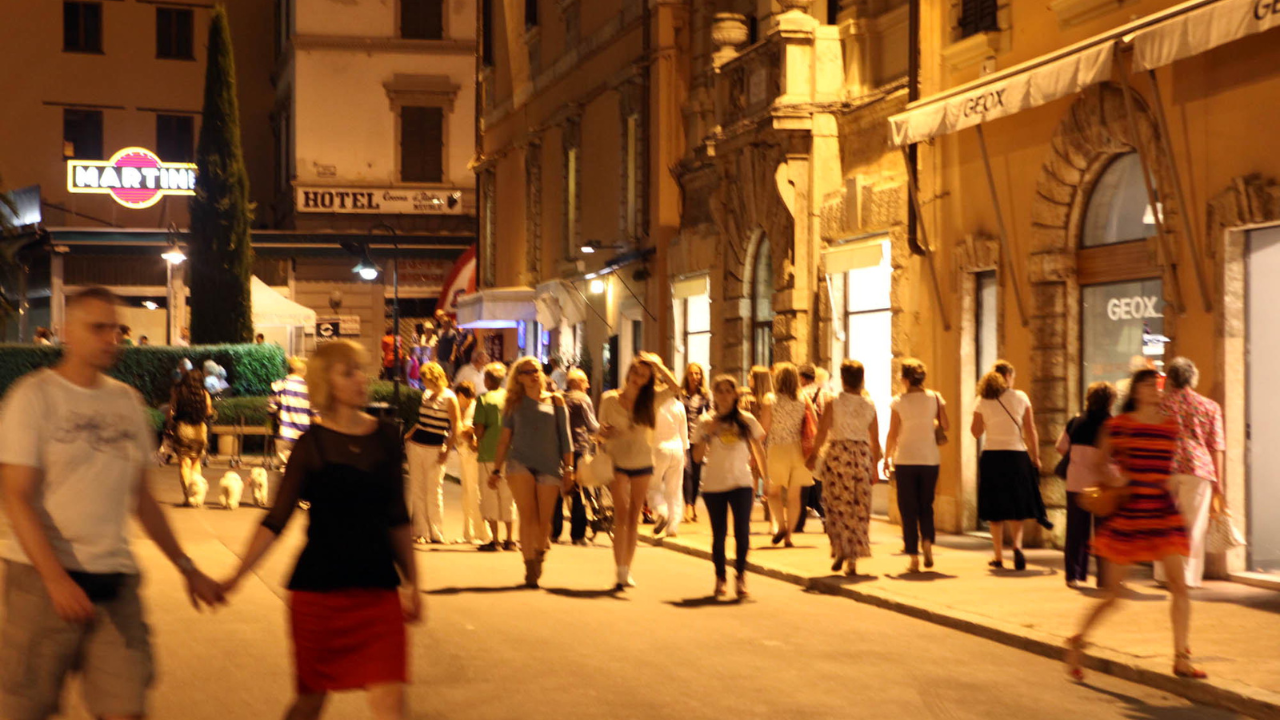 Visitatori la sera in centro con i negozi aperti