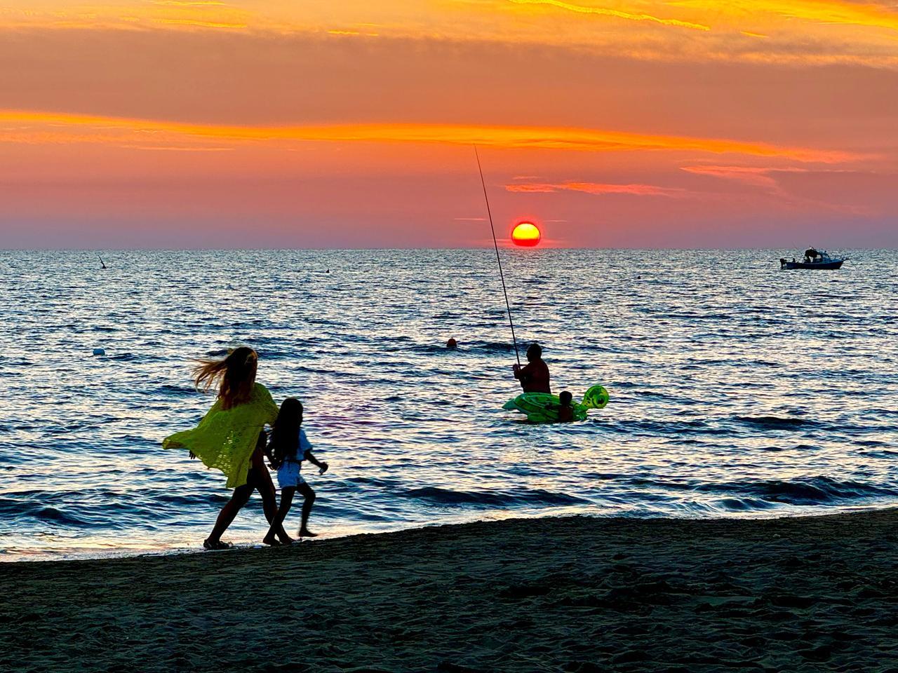C’è chi pesca e chi passeggia in spiaggia, a Livorno il tramonto è sempre uno show