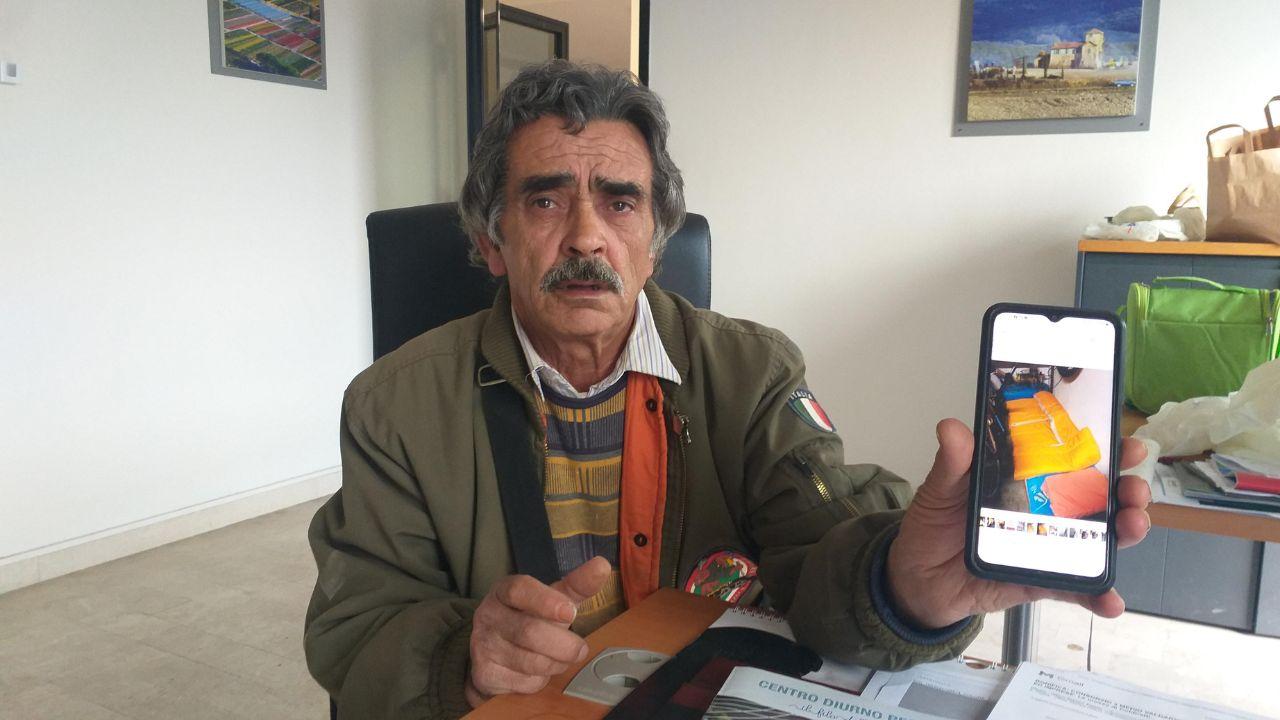 Antonino Longo mentre mostra la foto del materasso sui cui dorme sul pavimento