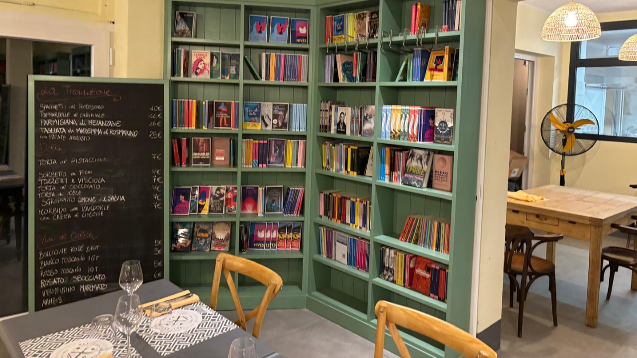Uno degli scaffali della libreria e accanto la lavagna con il menu nel locale che aprirà il 30 novembre