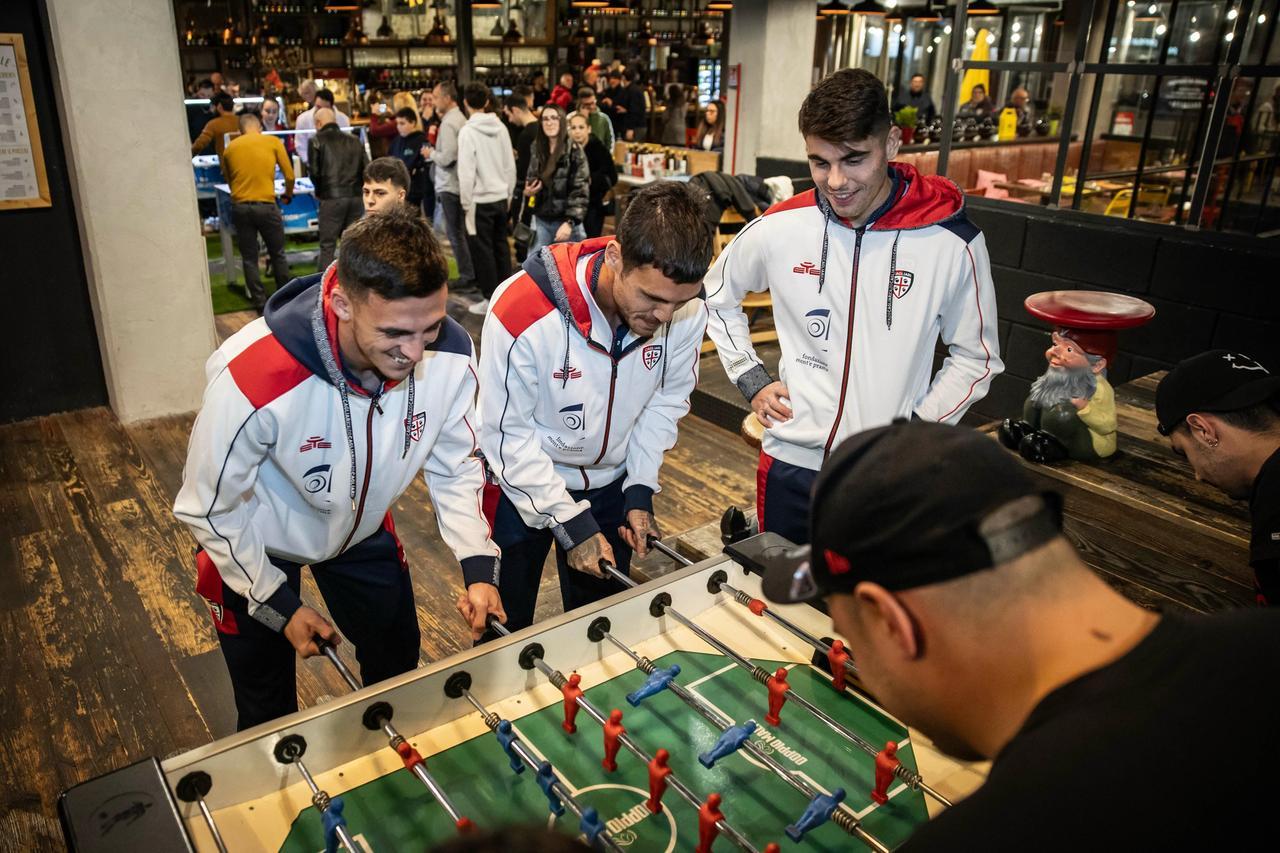 Nicolas Viola, Gabriele Zappa e Adam Obert giocano a calcio balilla con i tifosi del Cagliari
