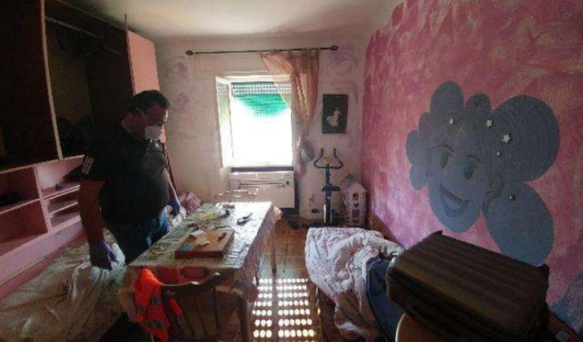 Un carabiniere nella camera da letto dell'alloggio dopo la morte di Denny Magina
