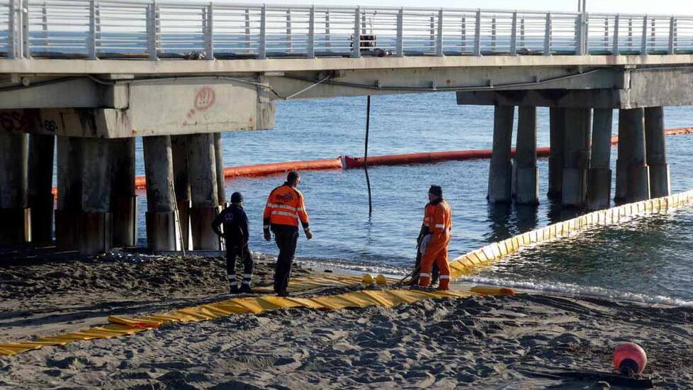 Qui i tecnici e gli operai al lavoro per disporre le panne contenitive intorno al pontile (foto Cuffaro)
