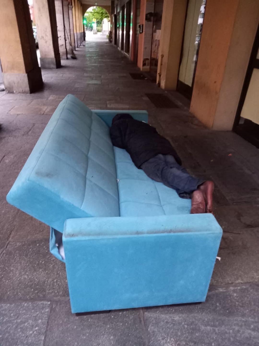Dorme su un divano sotto i portici di via Emilia San Pietro