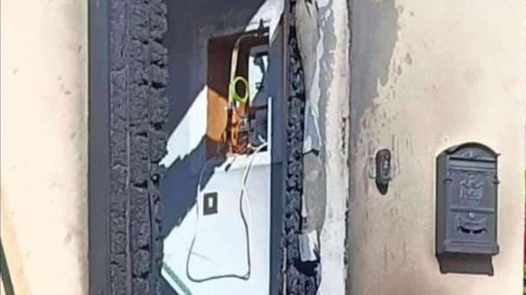 
	Il portone della casa distrutto dalle fiamme

