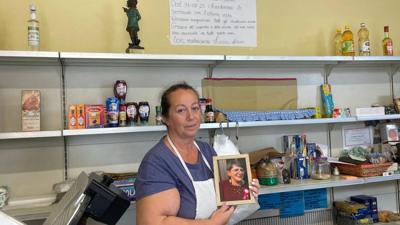 Lucia Puliti dietro il bancone del suo negozio: in mano la foto di Licia Mugnai