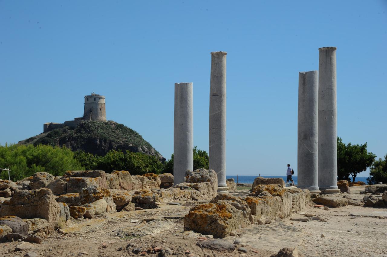 rovine di nora - Un turista si aggira tra i resti delle colonne che ricordano la maestosita' e lo splendore degli edifici romani