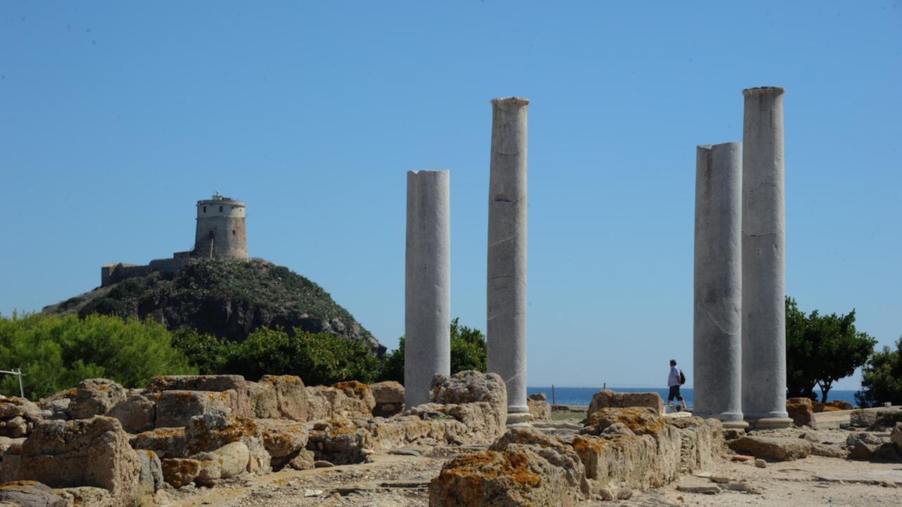 rovine di nora - Un turista si aggira tra i resti delle colonne che ricordano la maestosita' e lo splendore degli edifici romani