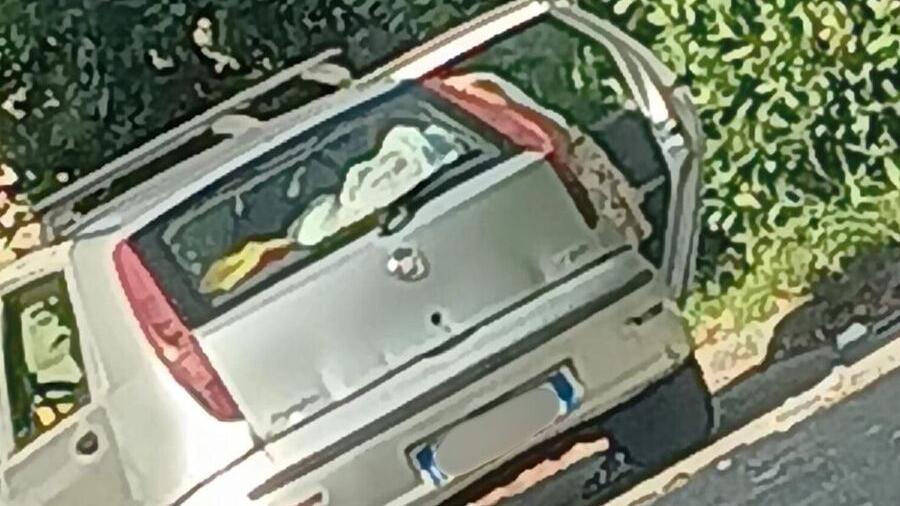 La donna mentre scarica i sacchi dalla sua auto per lasciarli nel parcheggio