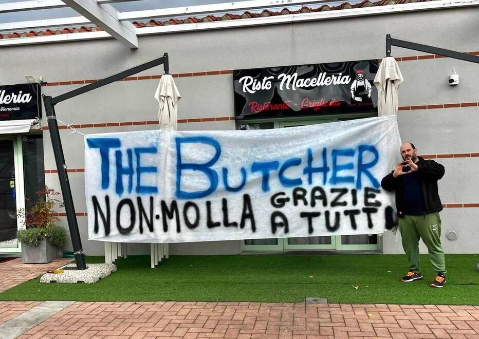 Il titolare e lo striscione fuori dal locale